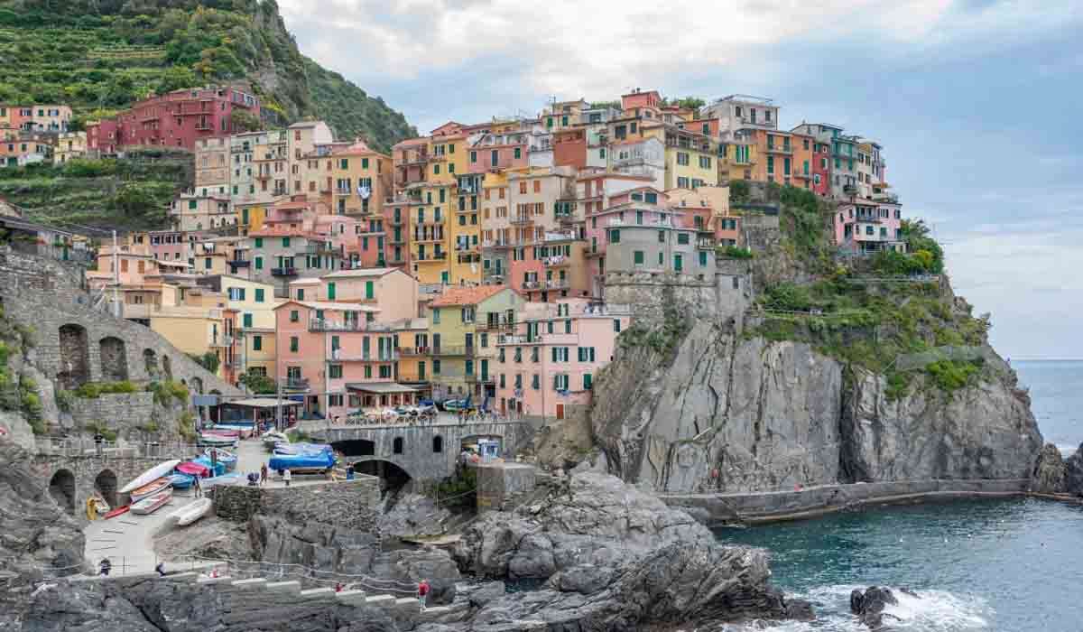 Panoramic view of Cinque Terre with the sunlit Path of Love trail overlooking the sea.