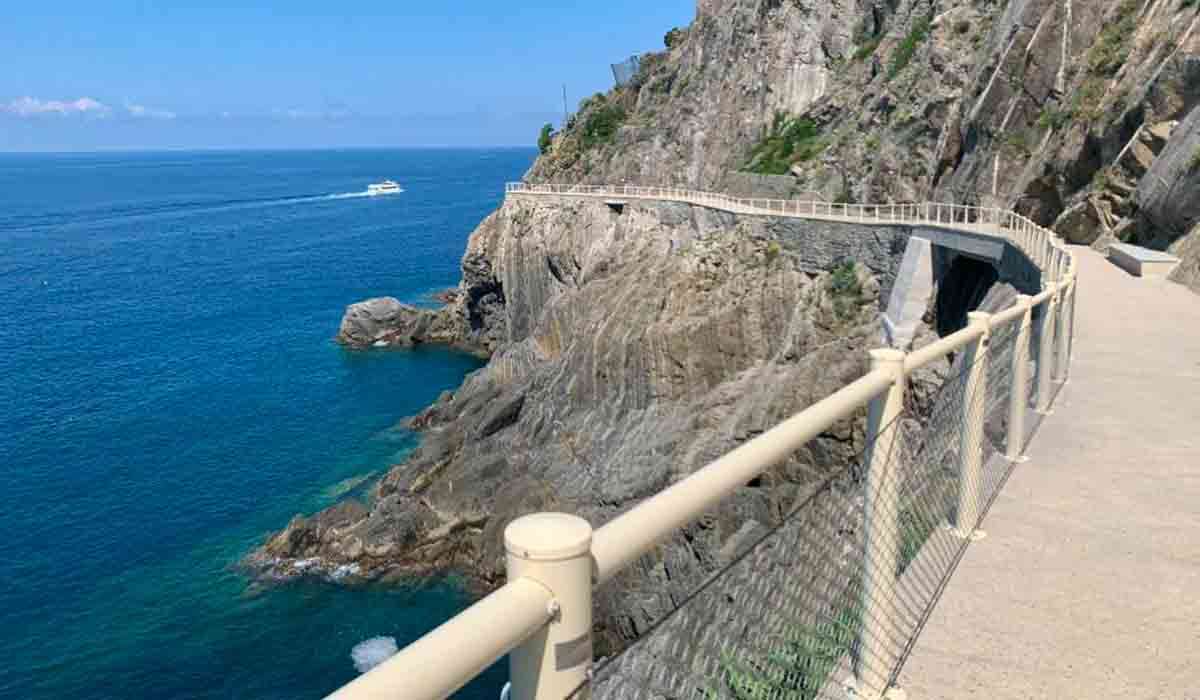 Panoramic view of Cinque Terre with the sunlit Path of Love trail overlooking the sea.